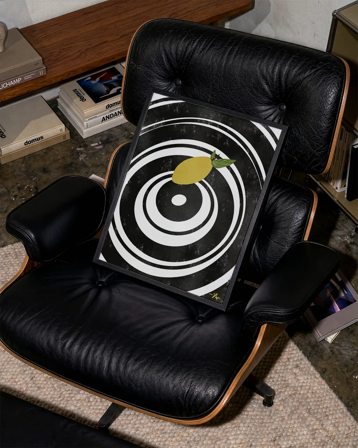 Black-framed target print with lemon slice graphic, leaning on a black chair